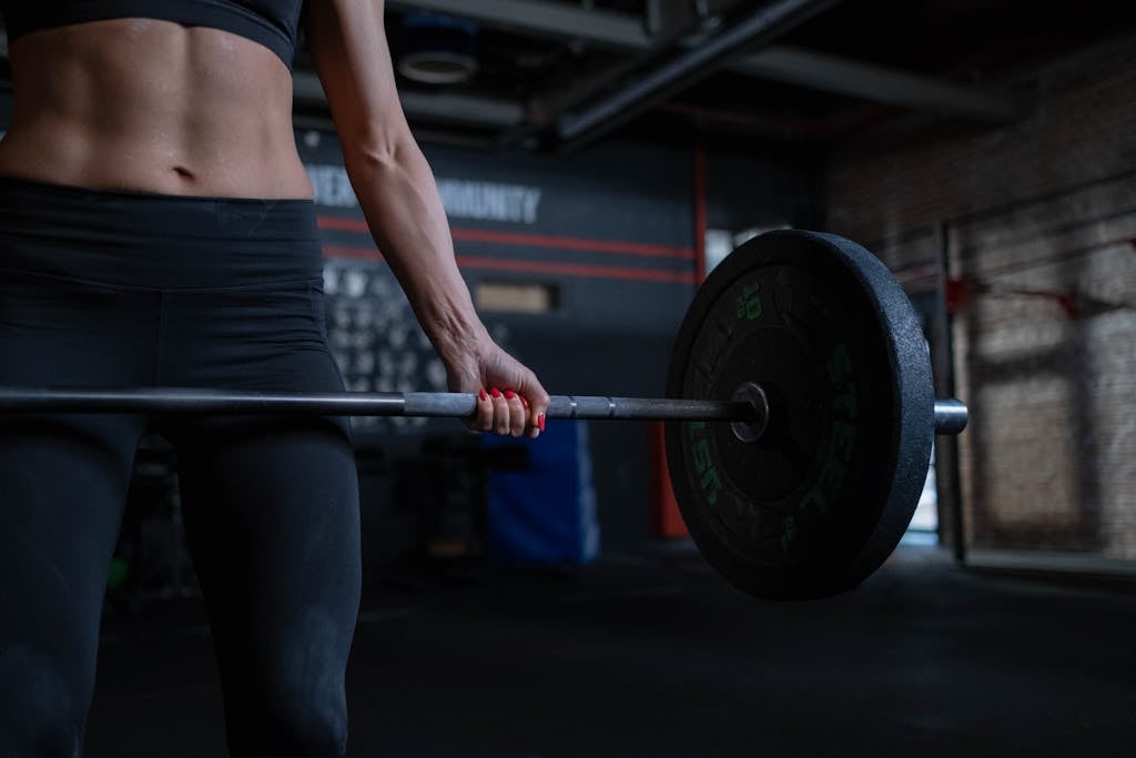 Woman in Black Sportswear Lifting a Barbell